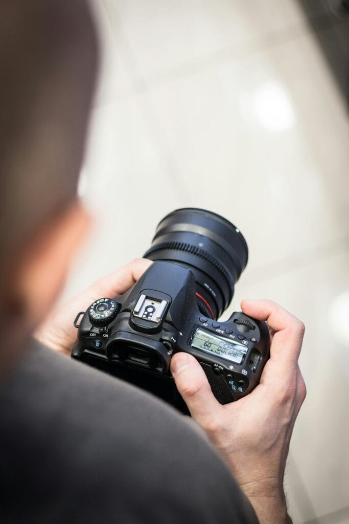 Person adjusting DSLR camera settings indoors for photography.