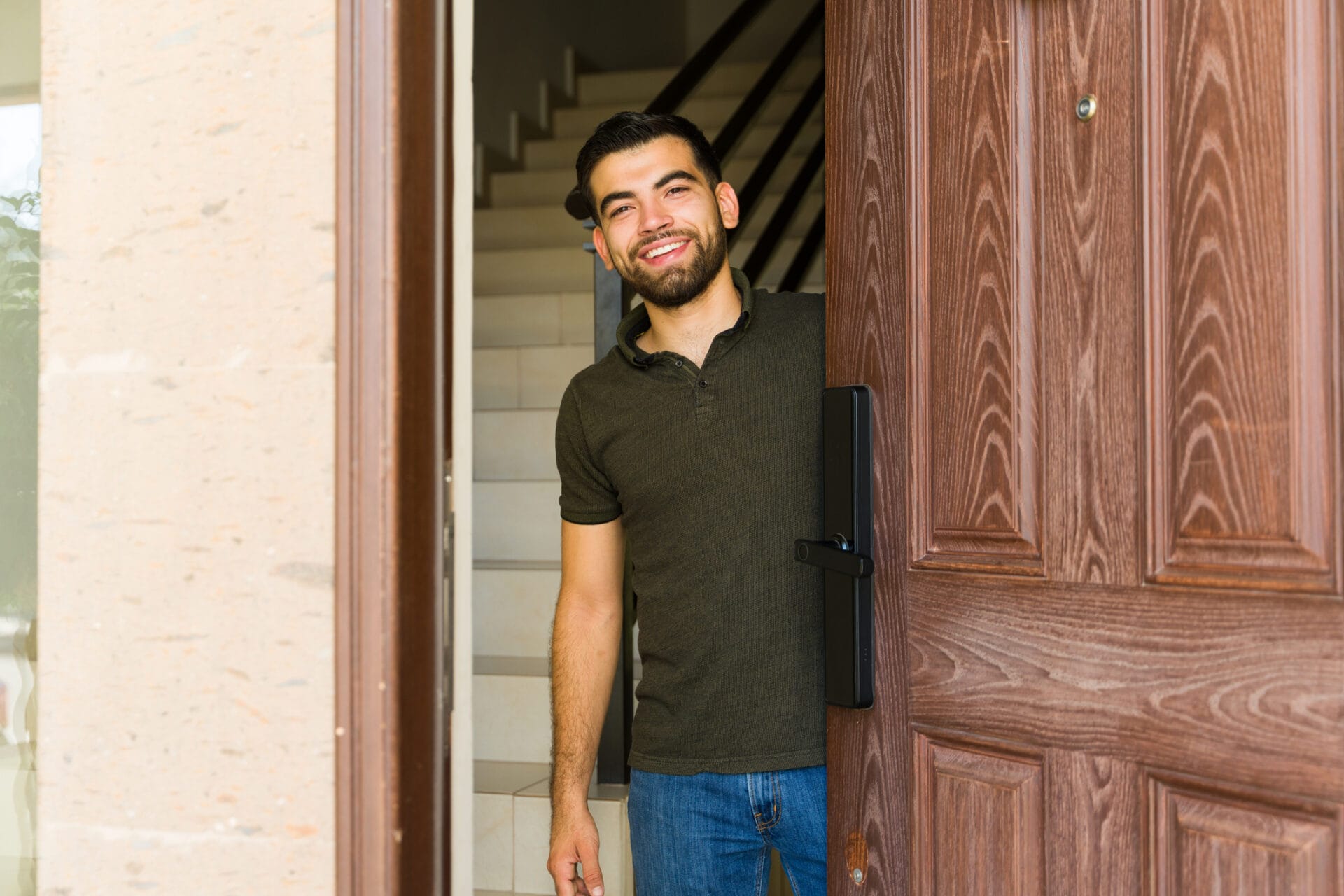 Hispanic man welcoming with a smile at his front door, creating a warm atmosphere for guests